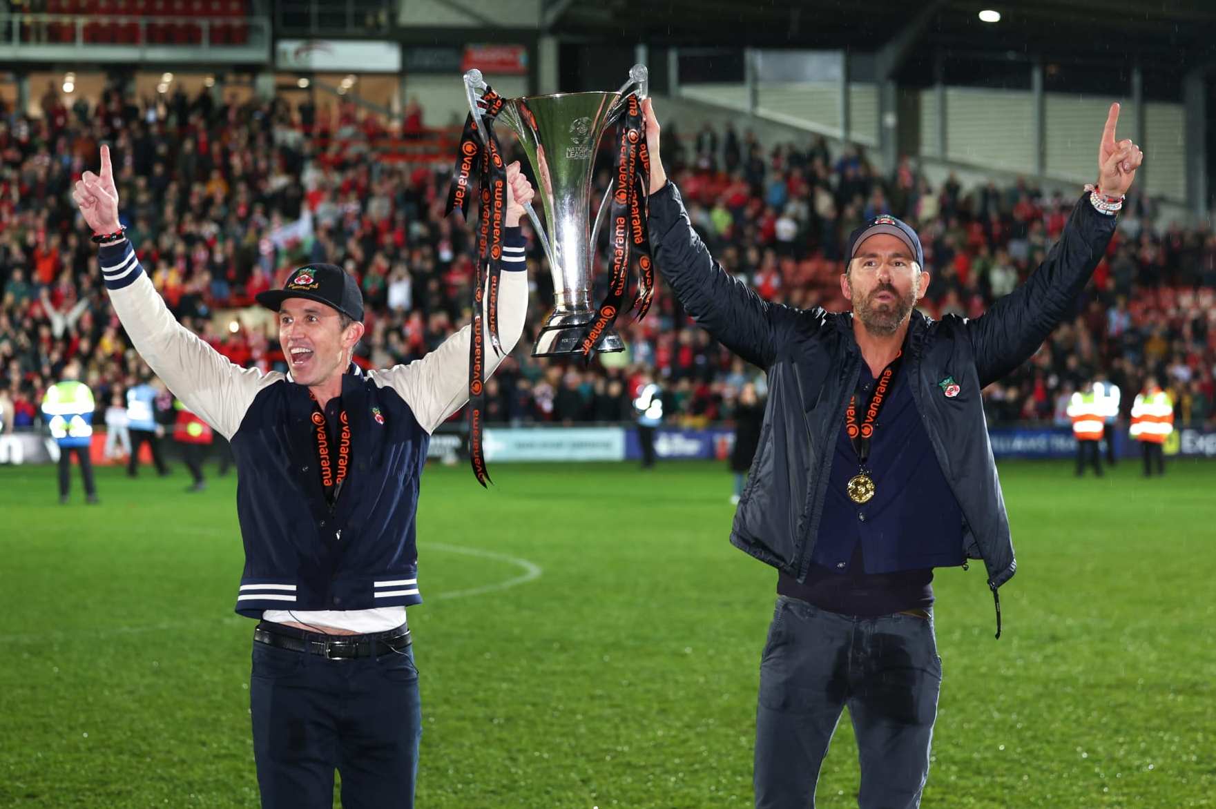 WREXHAM, WALES - APRIL 22: Ryan Reynolds co-owner of Wrexham and Rob McElhenney co-owner of Wrexham with the Vanarama National League Trophy as Wrexham celebrate promotion back to the English Football League during the Vanarama National League match between Wrexham and Boreham Wood at Racecourse Ground on April 22, 2023 in Wrexham, Wales. (Photo by Matthew Ashton - AMA/Getty Images)