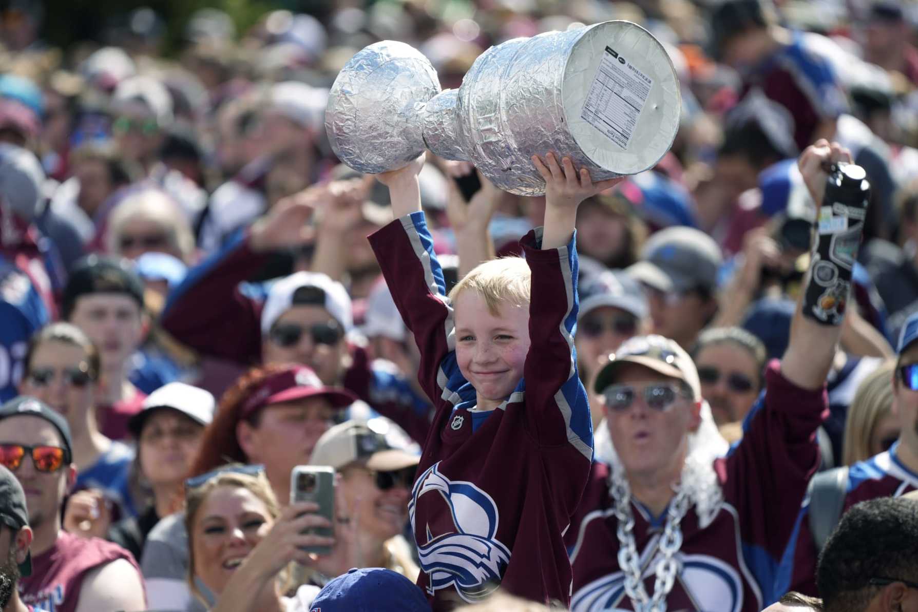 A Colorado Avalanche fan holds up a replica of the Stanley Cup during a rally outside the City/County Building for the NHL hockey champions after a parade through the streets of downtown Thursday, June 30, 2022, in Denver. (AP Photo/David Zalubowski)