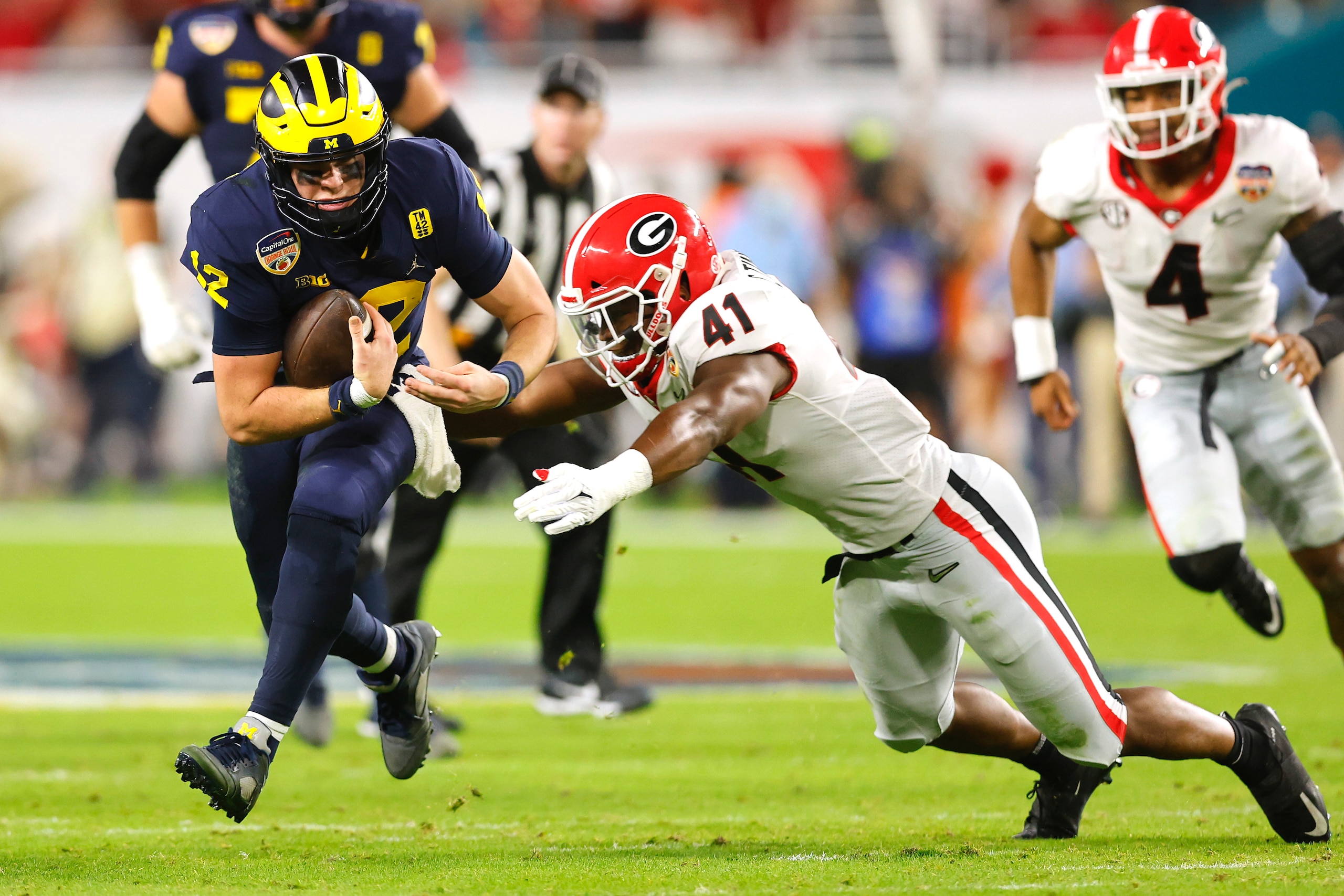 MIAMI GARDENS, FLORIDA - DECEMBER 31: Cade McNamara #12 of the Michigan Wolverines is tackled by Channing Tindall #41 of the Georgia Bulldogs in the second quarter of the game in the Capital One Orange Bowl for the College Football Playoff semifinal game at Hard Rock Stadium on December 31, 2021 in Miami Gardens, Florida. (Photo by Michael Reaves/Getty Images)