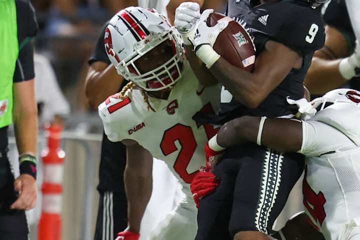 HONOLULU, HI - SEPTEMBER 03: Dior Scott #9 of the Hawaii Rainbow Warriors makes a catch as he is tackled by Upton Stout #21 and Derrick Smith #24 of the Western Kentucky Hilltoppers during the first half of an NCAA football game at the Clarance T.C. Ching Athletic Complex on September 3, 2022 in Honolulu, Hawaii. (Photo by Darryl Oumi/Getty Images)