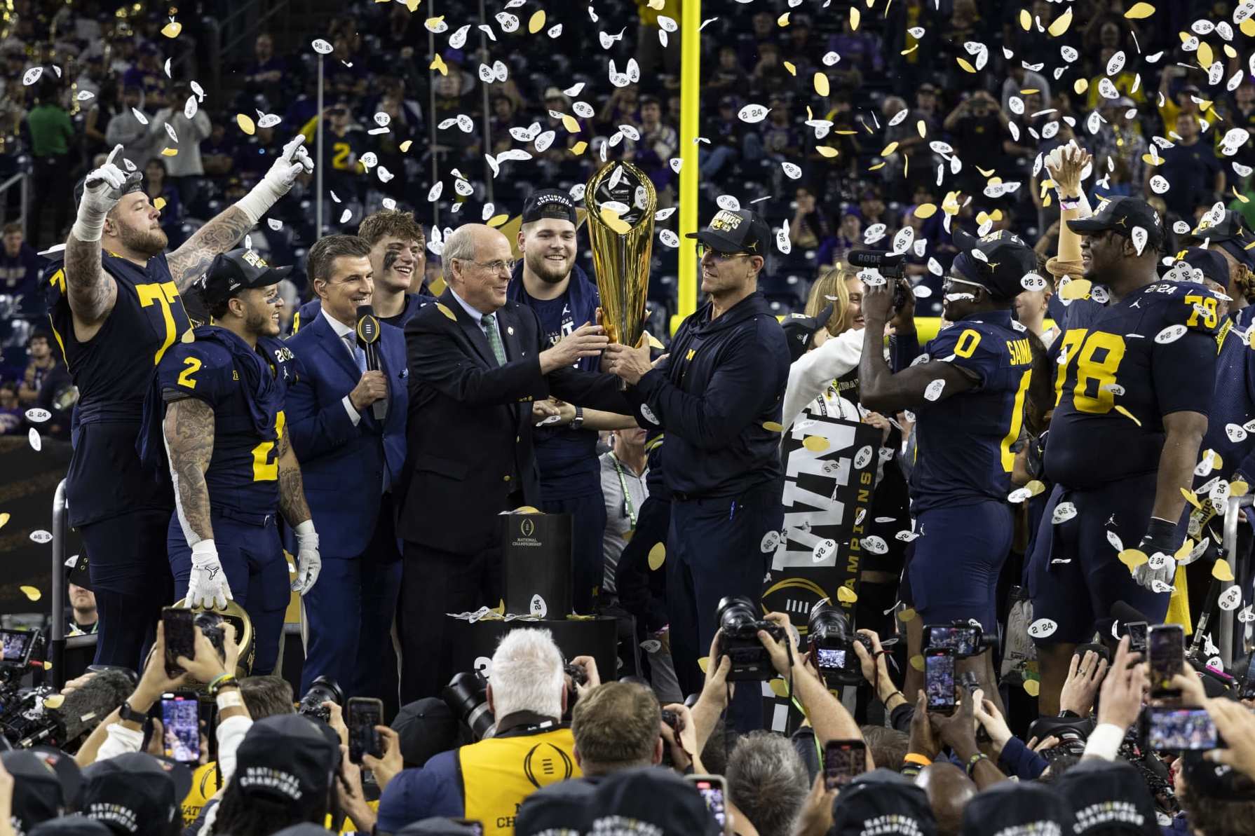 HOUSTON, TX - JANUARY 8: Head Coach Jim Harbaugh of the Michigan Wolverines is presented the trophy as National Champion after the CFP National Championship game between University of Washington and University of Michigan at NRG Stadium on January 8, 2024 in Houston, Texas. (Photo by Steve Limentani/ISI Photos/Getty Images)