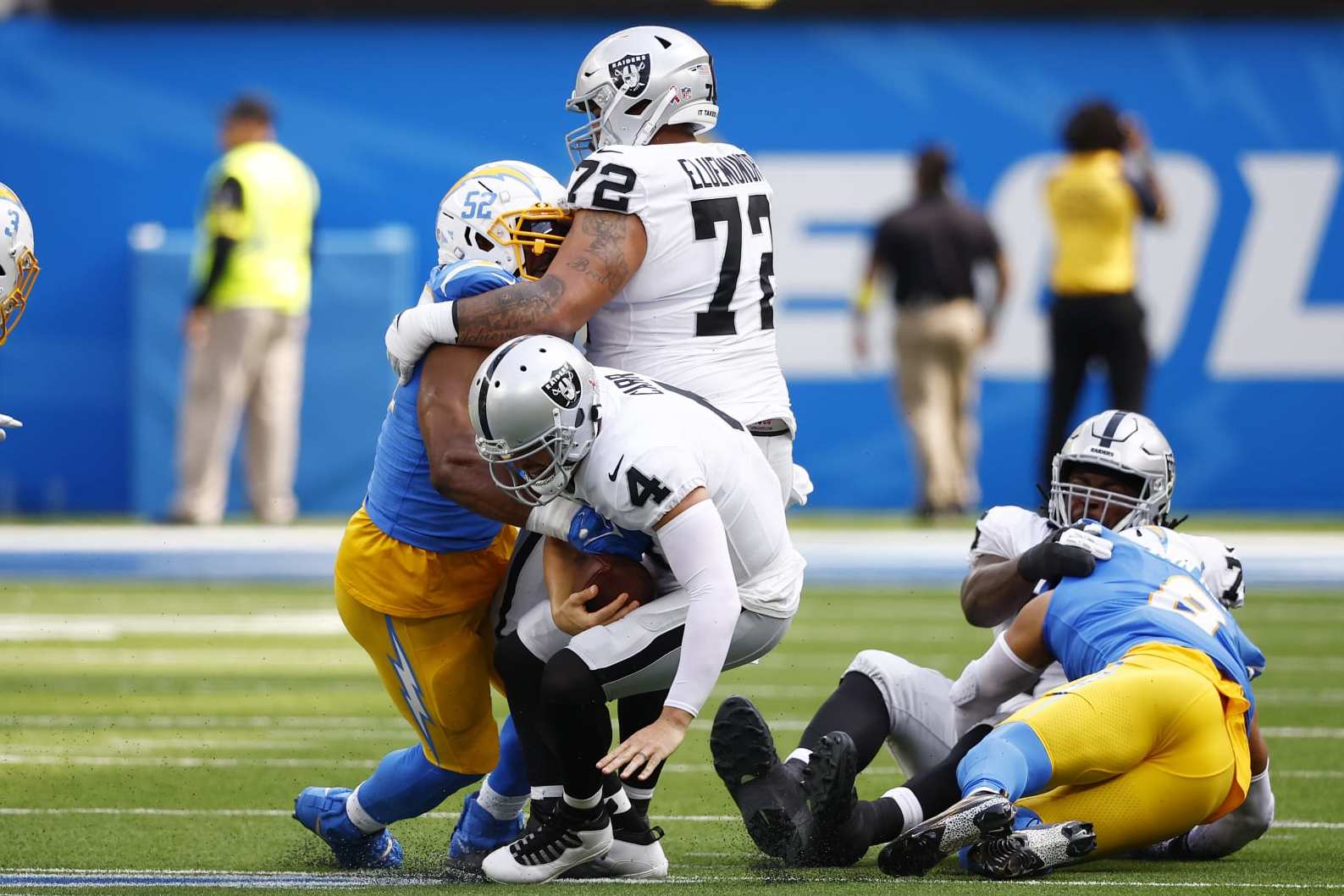 INGLEWOOD, CALIFORNIA - SEPTEMBER 11: Linebacker Khalil Mack #52 of the Los Angeles Chargers and guard Jermaine Eluemunor #72 of the Las Vegas Raiders fall on top of quarterback Derek Carr #4 of the Las Vegas Raiders during the first half at SoFi Stadium on September 11, 2022 in Inglewood, California. (Photo by Ronald Martinez/Getty Images)