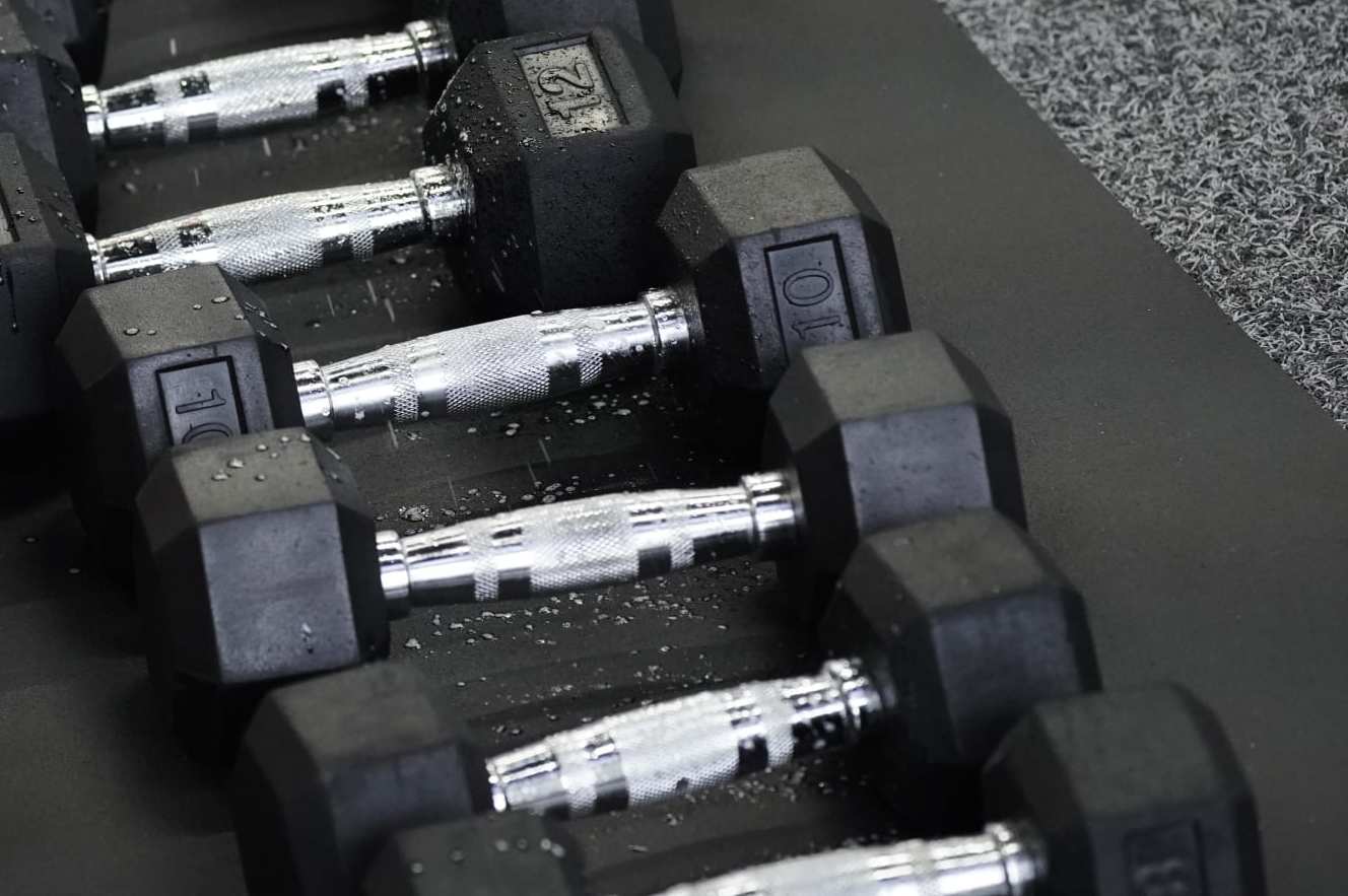 A person disinfects dumbbells inside a temporary social distancing pod at Inspire South Bay Fitness in Redondo Beach, California, U.S., on Friday, June 19, 2020. In addition to cutting class sizes, the gym has created individual plastic workout pods for people to take classes while still maintaining social distance, CNN reported. Photographer: Bing Guan/Bloomberg via Getty Images