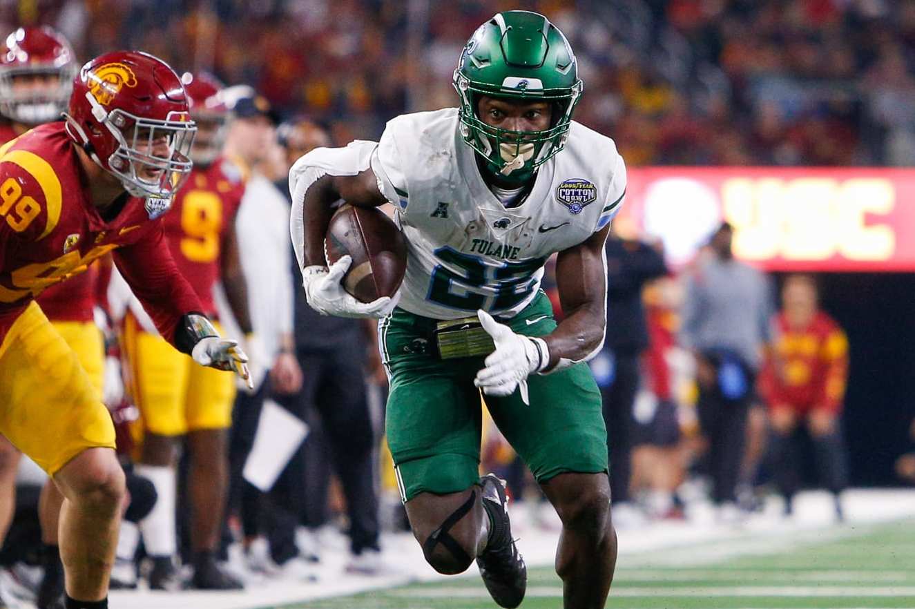 ARLINGTON, TX - JANUARY 02: Tulane Green Wave running back Tyjae Spears (22) breaks free from an attempted tackle by USC Trojans defensive lineman Nick Figueroa (99) during the Cotton Bowl game between the Tulane Green Wave and USC Trojans on January 2, 2023 at AT&T Stadium in Arlington, TX.  (Photo by Andrew Dieb/Icon Sportswire via Getty Images)