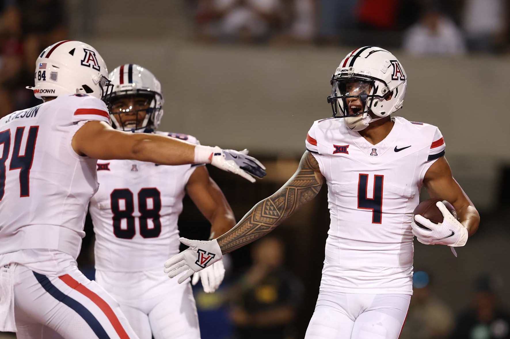 TUCSON, ARIZONA - AUGUST 31: Wide receiver Tetairoa McMillan #4 of the Arizona Wildcats high fives tight end Sam Olson #84 after scoring a touchdown during the first half against the New Mexico Lobos at Arizona Stadium on August 31, 2024 in Tucson, Arizona. McMillan set the Arizona single game receiving record, finishing with 304 receiving yards on 10 catches. The Wildcats defeated the Lobos 61-39. (Photo by Chris Coduto/Getty Images)