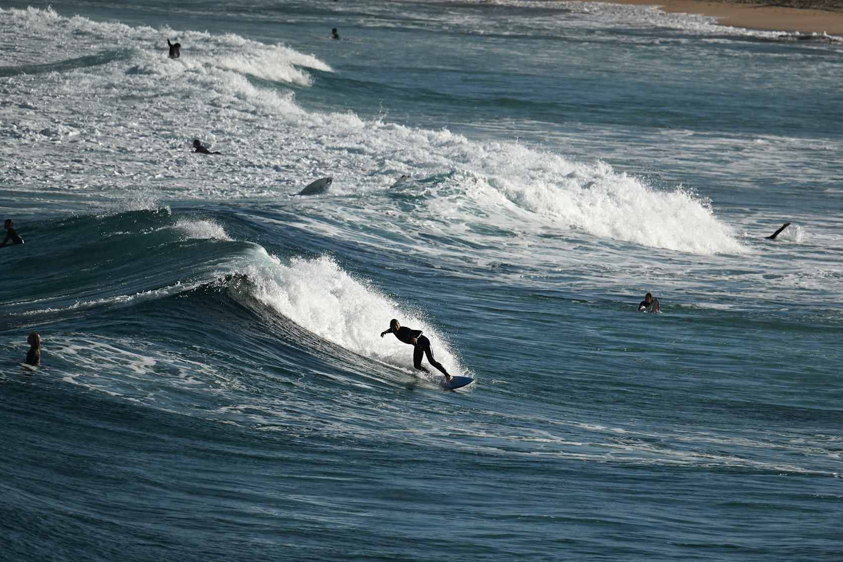 This picture taken on October 16, 2024, shows surfers riding the waves on Maroubra Beach after authorities closed down two adjacent beaches in Sydney. Authorities were baffled earlier this week when thousands of black spheres -- sized between a golf ball and a tennis ball -- were found littering the shores of tourist haven Coogee Beach, that later identified as petroleum-based "tar balls", after chemical testing. (Photo by Saeed KHAN / AFP) (Photo by SAEED KHAN/AFP via Getty Images)