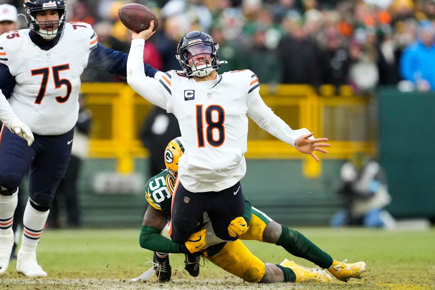 GREEN BAY, WISCONSIN - JANUARY 05: Caleb Williams #18 of the Chicago Bears throws a pass while being tackled by Edgerrin Cooper #56 of the Green Bay Packers in the fourth quarter at Lambeau Field on January 05, 2025 in Green Bay, Wisconsin. (Photo by Patrick McDermott/Getty Images)
