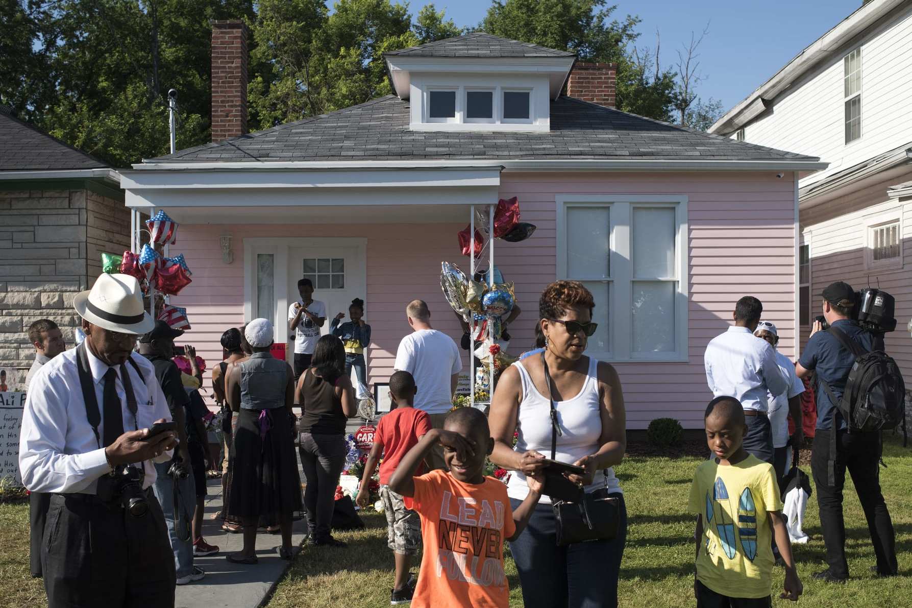 LOUISVILLE, KY - JUNE 10: People gather on Grand Avenue in front of Muhammad Ali's childhood home waiting for the funeral procession motorcade for Ali on June 10, 2016 in Louisville, Kentucky. The funeral procession for Ali was traveling over 20 miles on a designated route throughout Louisville on the way to Cave Hill Cemetery. The four-time world heavyweight boxing champion died on June 3 at age 74. (Photo by Ty Wright/Getty Images)