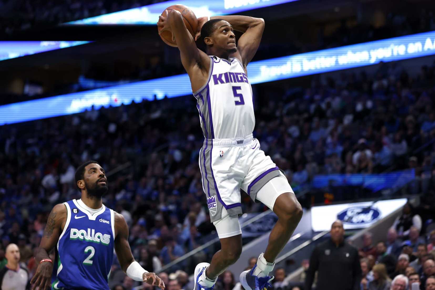 DALLAS, TX - APRIL 5: DeAaron Fox #5 of the Sacramento Kings scores on a break away slam dunk as Kyrie Irving #2 of the Dallas Mavericks looks on in the first half at American Airlines Center on April 5, 2023 in Dallas, Texas. NOTE TO USER: User expressly acknowledges and agrees that, by downloading and or using this photograph, User is consenting to the terms and conditions of the Getty Images License Agreement. (Photo by Ron Jenkins/Getty Images)