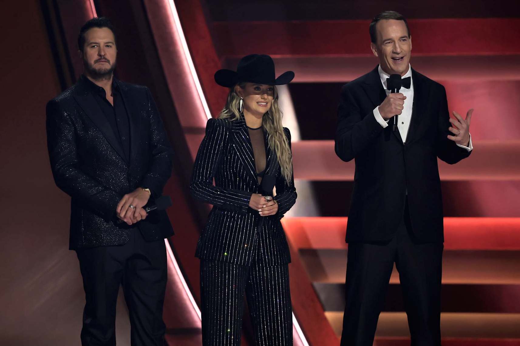 NASHVILLE, TENNESSEE - NOVEMBER 20: EDITORIAL USE ONLY (L-R) Luke Bryan, Lainey Wilson and Peyton Manning speak onstage during The 58th Annual CMA Awards at Bridgestone Arena on November 20, 2024 in Nashville, Tennessee. (Photo by Theo Wargo/Getty Images)