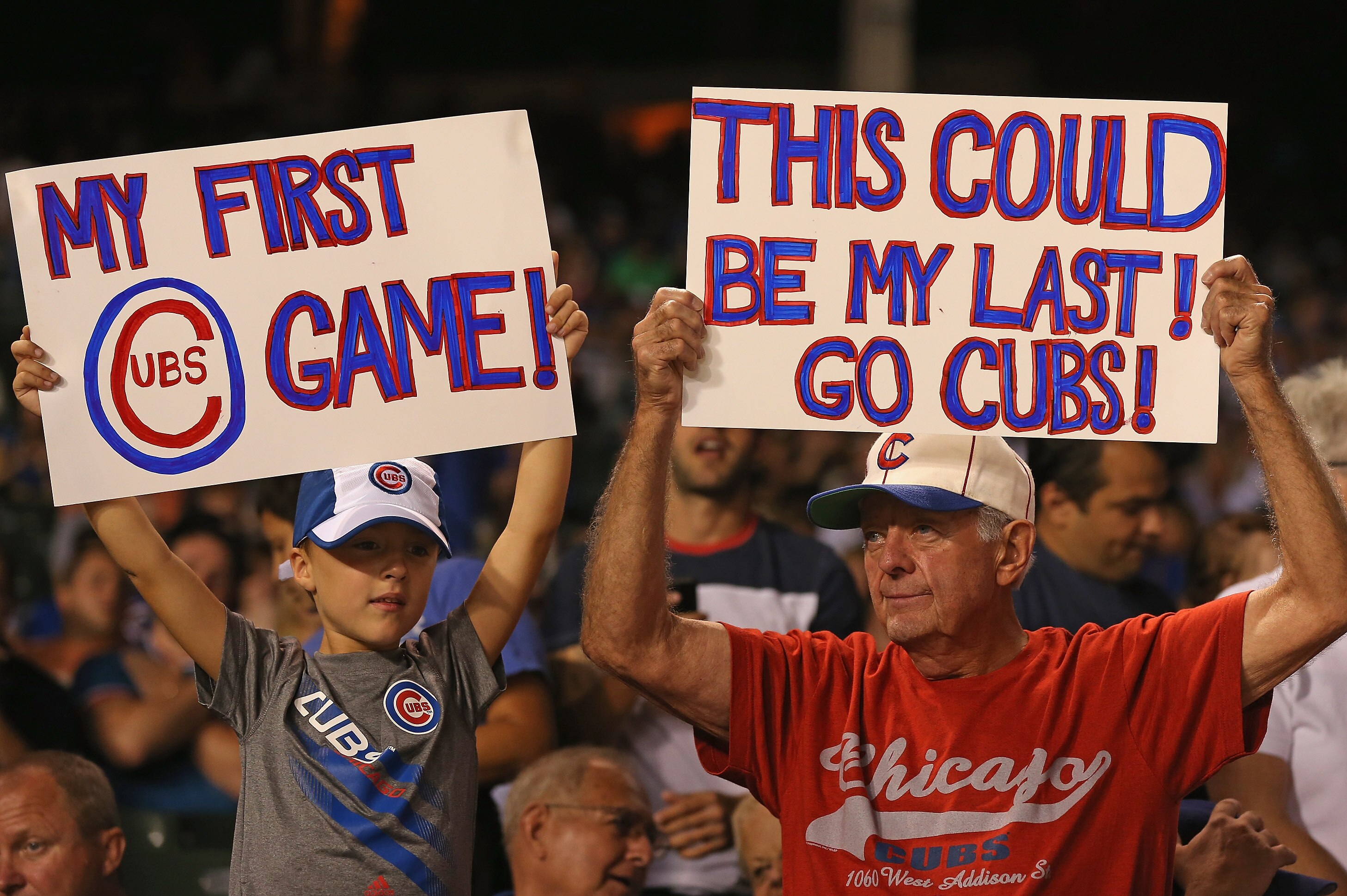 CHICAGO, IL - AUGUST 27: Jim Dolan of Aurora, Illinois (R) and his grandson Andrew Naster, hold signs as the Chicago Cubs take on the Milwaukee Brewers at Wrigley Field on August 27, 2012 in Chicago, Illinois. (Photo by Jonathan Daniel/Getty Images)