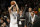 Brooklyn Nets' Bojan Bogdanovic (44), of Croatia, makes a 3-point basket as Milwaukee Bucks' Jerryd Bayless, right, yells at him from the bench during the overtime period of an NBA basketball game Friday, March 20, 2015, in New York. The Nets won the game 129-127. (AP Photo/Frank Franklin II)