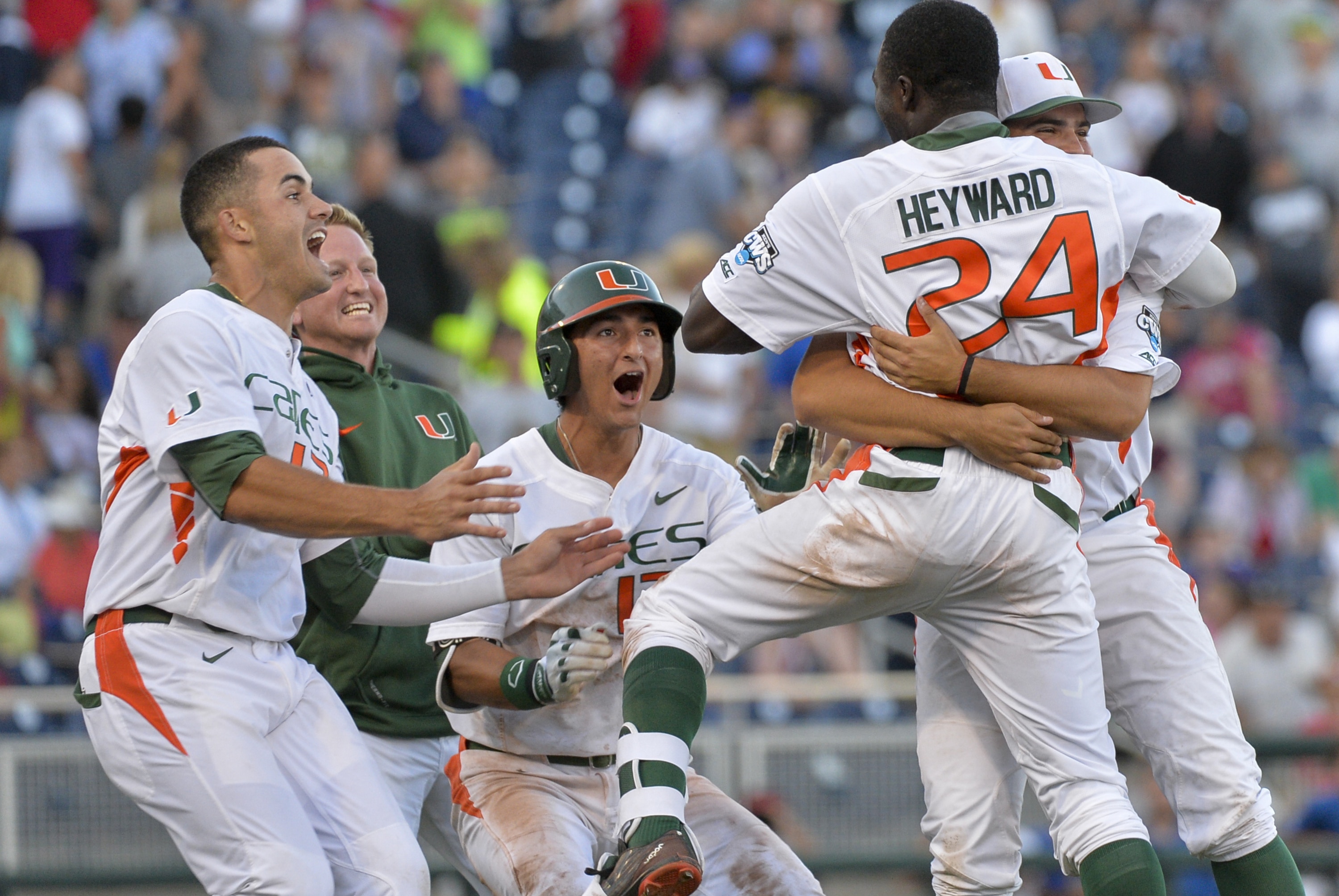 Miami's Willie Abreu, left, celebrates with Jacob Heyward (24), whose single scored Carl Chester during the ninth inning of an NCAA College World Series baseball elimination game against Arkansas in Omaha, Neb., Monday, June 15, 2015. Miami won 4-3. (AP Photo/Ted Kirk)