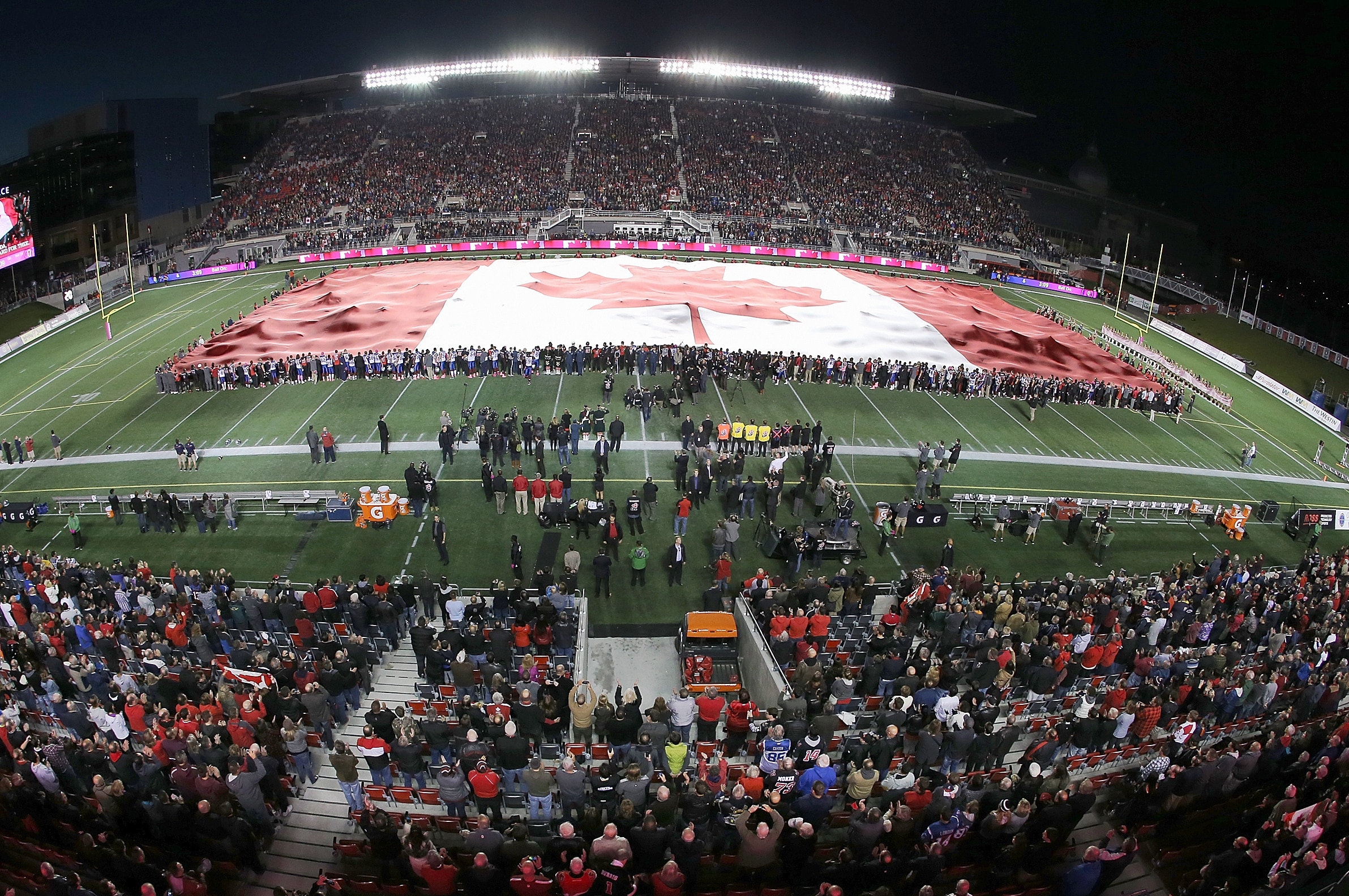 OTTAWA, ON - OCTOBER 24: The largest Canadian flag in the world is unfurled to show solidarity after the terror attack in Ottawa earlier in the week, prior to the game between the Ottawa Redblacks and the Montreal Alouettes at TD Place Stadium on October 24, 2014 in Ottawa, Ontario, Canada. (Photo by Jana Chytilova/Freestyle Photography/Getty Images)