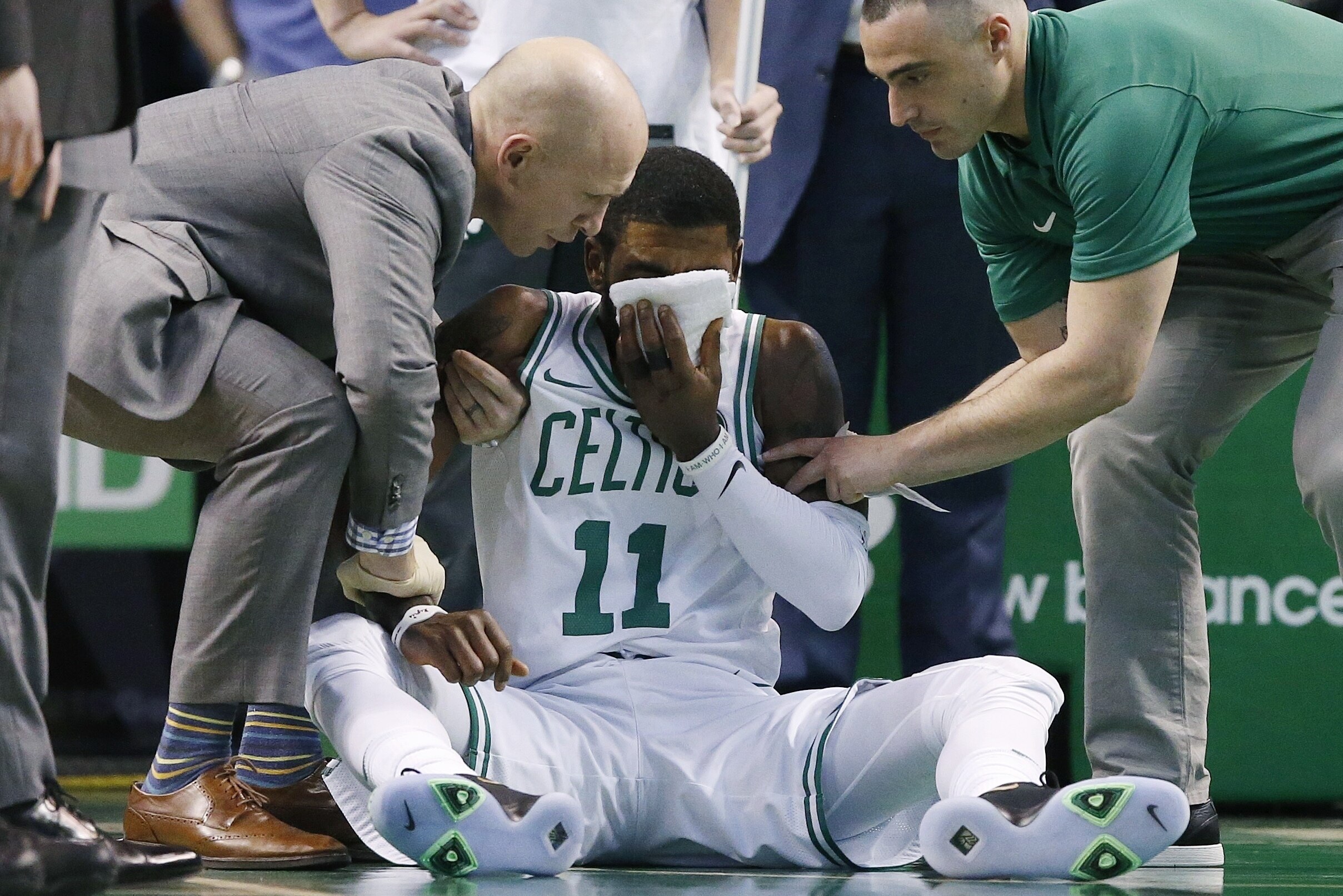Team personnel assist Boston Celtics' Kyrie Irving (11) after he was injured during the first quarter of an NBA basketball game against the Charlotte Hornets in Boston, Friday, Nov. 10, 2017. Irving took an elbow to the face and left the game. (AP Photo/Michael Dwyer)