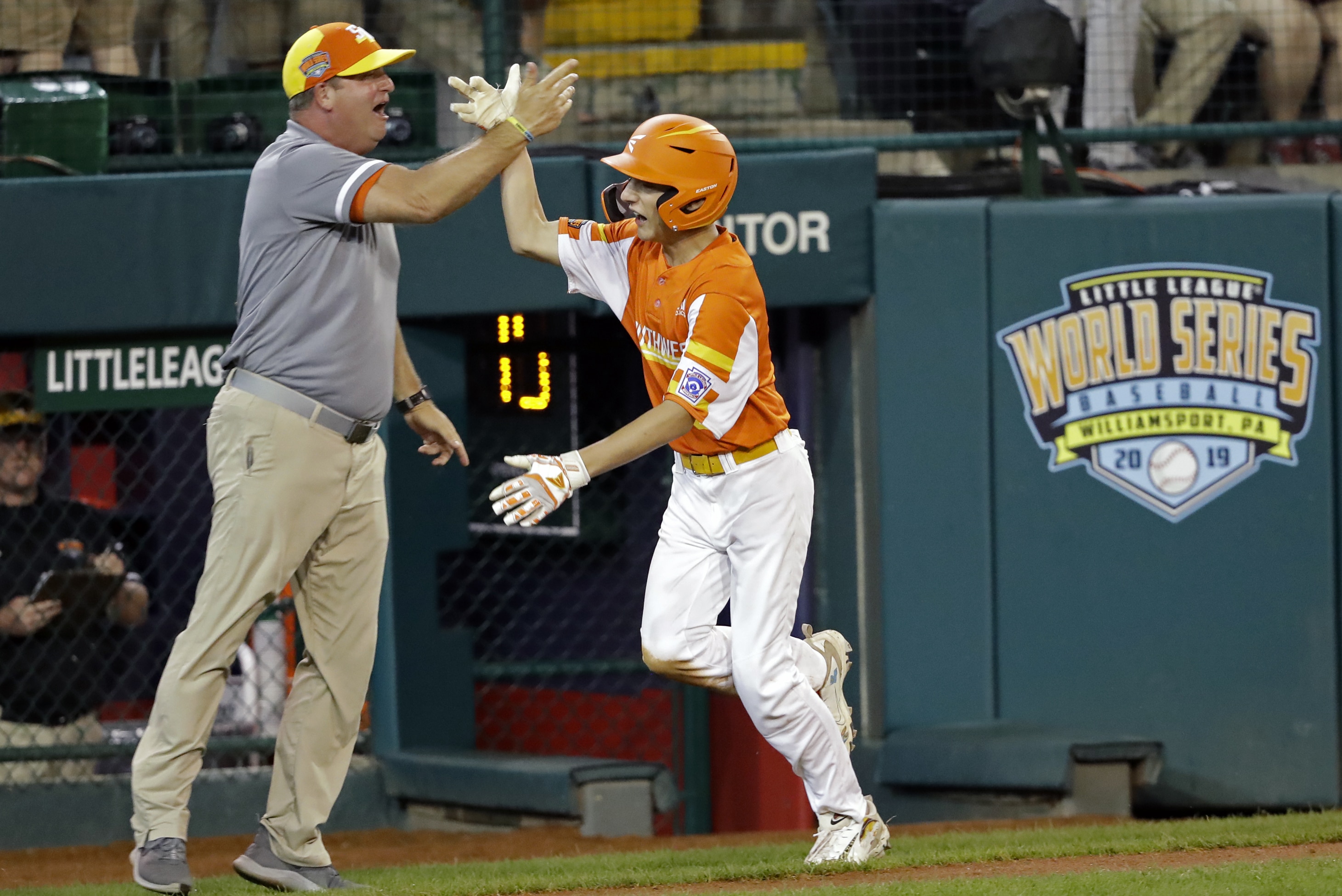 River Ridge, Louisiana's Reece Roussel (22) gets a high five from manager Scott Frazier as he rounds the base on his grand slam home run off of South Riding, Virginia's Justin Lee during the fourth inning of a baseball game at the Little League World Series tournament in South Williamsport, Pa., Thursday, Aug. 22, 2019. River Ridge, Louisiana won the game 10-0. (AP Photo/Tom E. Puskar)