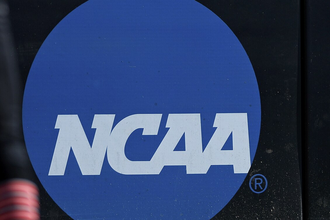 FILE - In this April 19, 2019, file photo, an athlete stands near a NCAA logo during a softball game in Beaumont, Texas. California will let college athletes hire agents and make money from endorsements, defying the NCAA and setting up a likely legal challenge that could reshape U.S. amateur sports. (AP Photo/Aaron M. Sprecher, File)