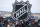 FILE - In this Saturday, Feb. 15, 2020, file photo, fans pose below the NHL league logo at a display outside Falcon Stadium before an NHL Stadium Series outdoor hockey game between the Los Angeles Kings and Colorado Avalanche, at Air Force Academy, Colo. The NHL nailed down the final details of a playoff format if the season can resume on the same day word came out that another player has tested positive for the coronavirus. (AP Photo/David Zalubowski, File)