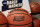 FILE - In this March 16, 2020, file photo, official March Madness 2020 tournament basketballs are displayed in a storeroom at the CHI Health Center Arena, in Omaha, Neb. The dominos started tumbling in March, when the NCAA abruptly called off March Madness, given no choice but to forgo a nearly $800 million TV payment that helps keep the entire college sports machine running. (AP Photo/Nati Harnik, File)