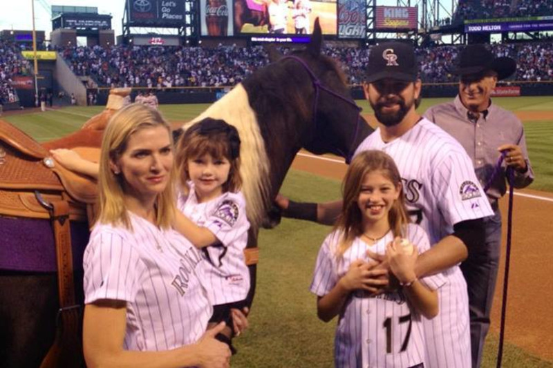 Seven-year-old Tierney Faith Helton, daughter of Colorado Rockies first  baseman Todd Helton, smiles after selecting gum from dispensers in the  dugout as she watches her father take part in a baseball workout