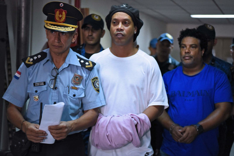 Brazilian retired football player Ronaldinho (C) and his brother Roberto Assis (R) arrive at Asuncion's Justice Palace to appear before a public prosecutor who will decide whether to grant them bail or not following their irregular entry to the country, i